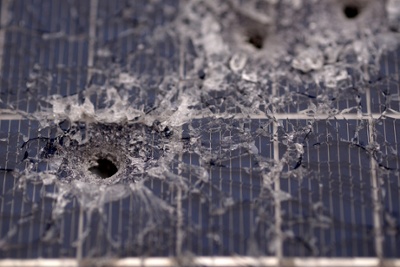 bullet hole in a solar panel with splintered glass