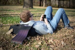 man charging his phone with a LightSaver while laying in the grass
