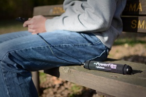 LightSaver Portable Solar Charger rolled up on a bench charging a cell phone