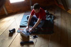 man on a MicroSoft surface working while it is being charged by  LightSaver Max Portable Solar Charger