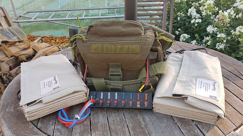 Lithium iron phosphate battery in a bag with an Anderson Powerpole strip and two 60W Foldable Solar Panels on a circular wooden table