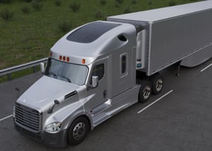 Silver semi-truck with a trailer parked on the road, featuring a solar panel installed on the roof of the cab