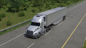 Silver semi-truck with trailer driving on a long straight road bordered by green trees with a solar panel on the fairing